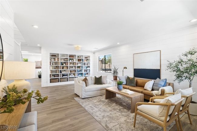 Living room with light wood-type flooring, wood walls, and recessed lighting | Image 4