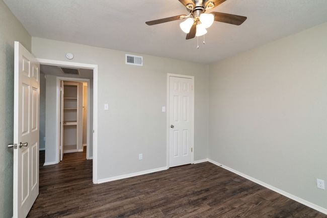Unfurnished bedroom featuring dark wood-style flooring, visible vents, and baseboards | Image 10