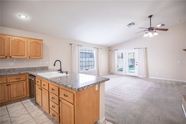 Kitchen with stainless steel dishwasher, a sink, visible vents, open floor plan, and a peninsula | Image 11