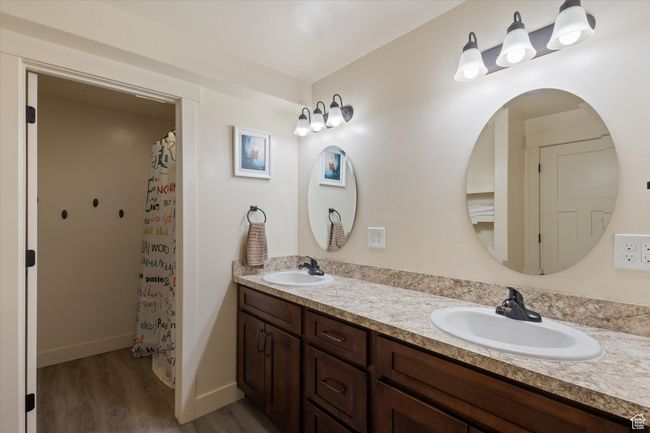 Full bath with double vanity, wood finished floors, baseboards, and a sink | Image 34