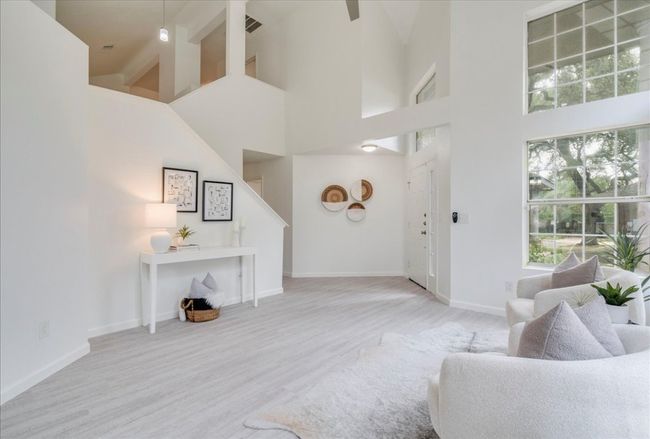 Living room with a high ceiling, wood finished floors, baseboards, and stairs | Image 7