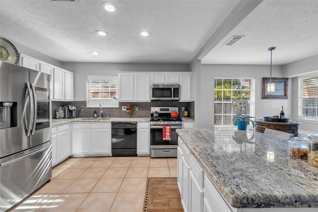 Impressive kitchen with a big island, ton of cabinets, stainless steel appliances and counter space. | Image 18