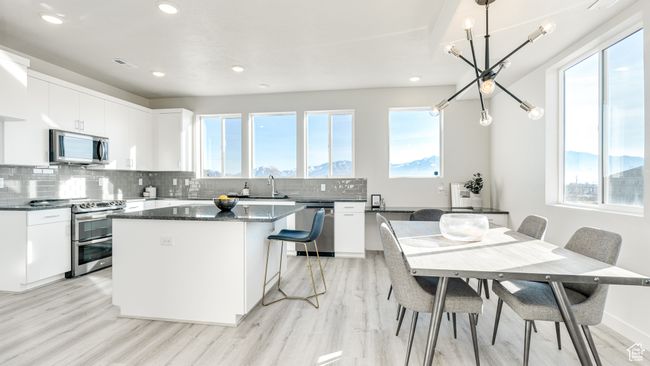 Kitchen featuring appliances with stainless steel finishes, a center island, light wood-style floors, tasteful backsplash, and recessed lighting | Image 7