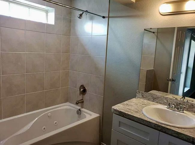 Bathroom featuring vanity, a combined bath / shower with jetted tub, and a textured wall | Image 12