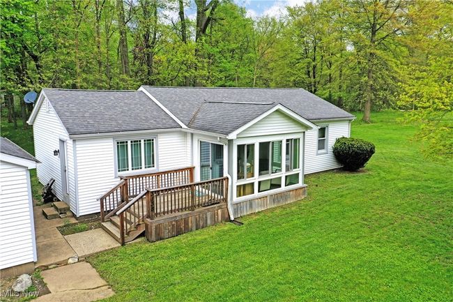 Rear view of house with roof with shingles, a deck, a yard, and a view of trees | Image 6