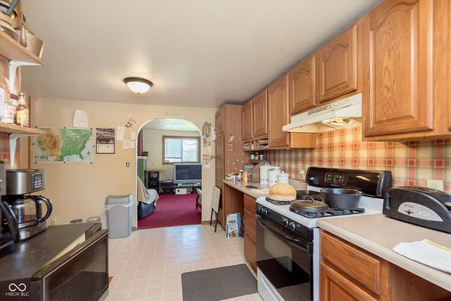 kitchen with light countertops, under cabinet range hood, range with gas cooktop, light floors, and arched walkways | Image 14