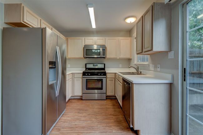 Kitchen featuring appliances with stainless steel finishes, a sink, light wood-style floors, light countertops, and light brown cabinets | Image 15