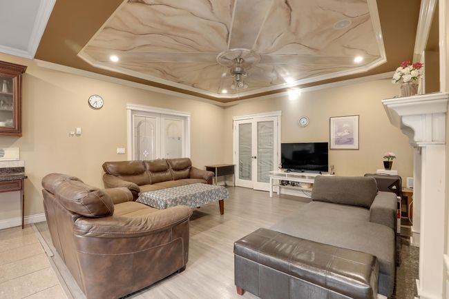 Living area with baseboards, ornamental molding, ceiling fan, and a tray ceiling | Image 13