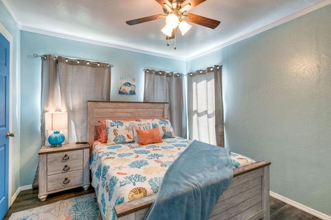 Bedroom with a ceiling fan, a textured wall, baseboards, and wood finished floors | Image 12