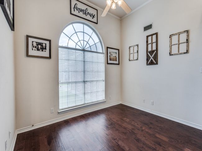 Unfurnished room featuring healthy amount of natural light, ceiling fan, crown molding, dark wood-type flooring, and baseboards | Image 5