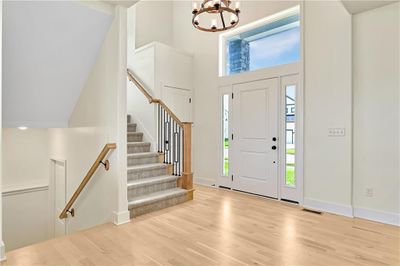 Entrance foyer featuring light hardwood flooring, a high ceiling, and a notable chandelier | Image 2