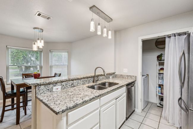Kitchen featuring stainless steel appliances, a peninsula, light tile patterned floors, and light stone counters | Image 7
