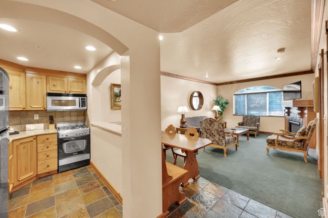 Kitchen featuring light brown cabinets, stone tile flooring, arched walkways, and appliances with stainless steel finishes | Image 16