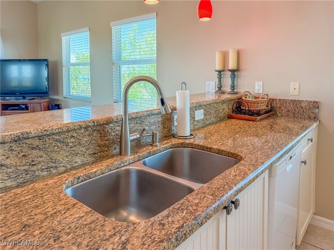 Kitchen featuring white dishwasher, a sink, white cabinetry, and light stone countertops | Image 14