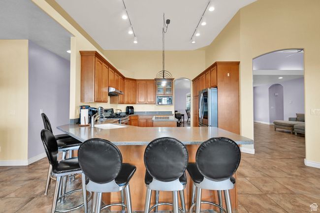 Kitchen with a sink, a peninsula, stainless steel appliances, under cabinet range hood, and arched walkways | Image 16