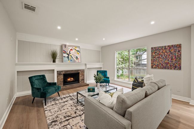 The living room features a cozy fireplace and built-in shelving. Crown molding and neutral walls give the space a polished look. | Image 17