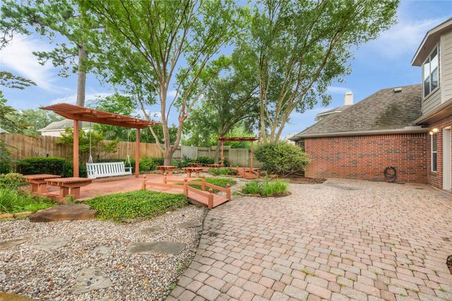 Expansive patio space connects to multiple garden paths, highlighted by a wooden deck and pergola swing. | Image 37