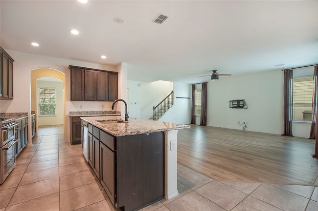 Kitchen featuring arched walkways, open floor plan, a kitchen island with sink, a ceiling fan, and light tile patterned flooring | Image 11
