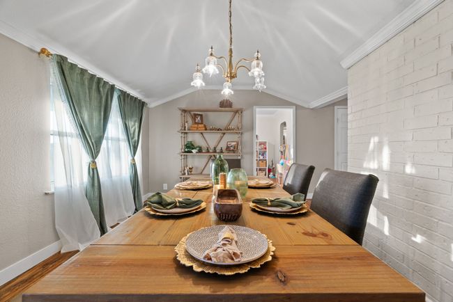 Dining room featuring a chandelier, ornamental molding, wood finished floors, and vaulted ceiling | Image 18