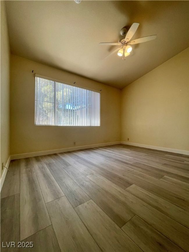 Unfurnished room featuring a ceiling fan, wood finished floors, a healthy amount of sunlight, and lofted ceiling | Image 6