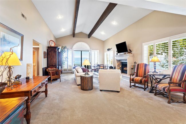 Living room with beamed ceiling, a warm lit fireplace, and high vaulted ceiling | Image 7