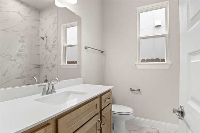 Bathroom featuring marble look tiles, vanity, toilet, baseboards, and a shower | Image 30