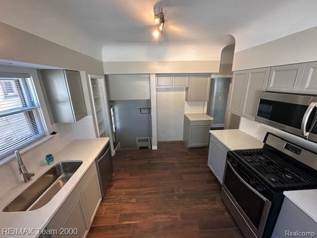 Kitchen featuring gray cabinets, stainless steel appliances, tasteful backsplash, and dark wood-style floors | Image 16