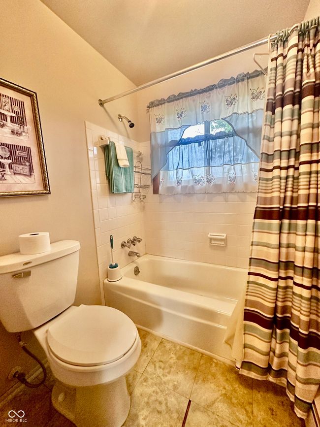 bathroom featuring shower / tub combo, toilet, and tile patterned flooring | Image 25