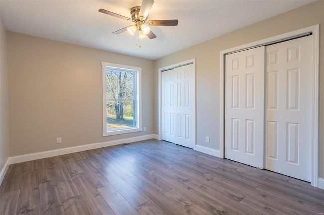 Unfurnished bedroom featuring multiple closets, ceiling fan, and wood-style floors | Image 17