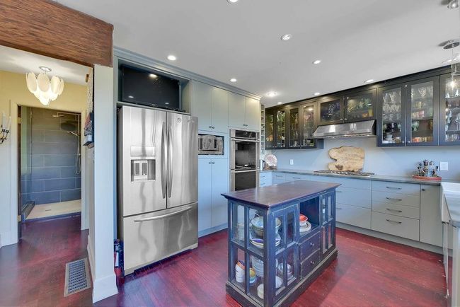 Kitchen featuring appliances with stainless steel finishes, under cabinet range hood, dark wood finished floors, glass insert cabinets, and recessed lighting | Image 15