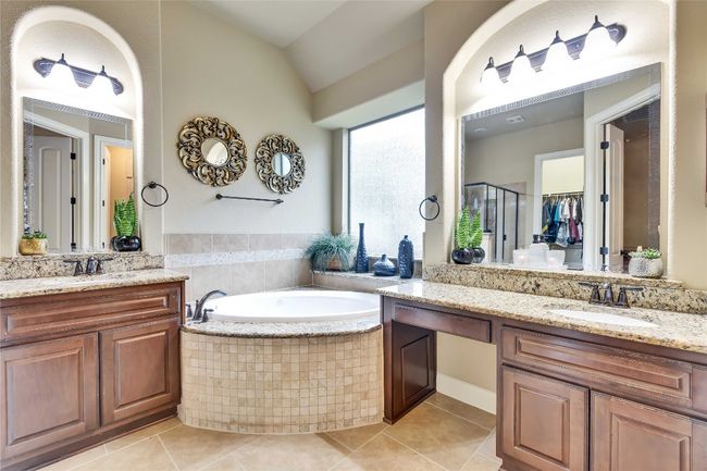 Owners full bathroom featuring large tile patterned floors, two vanities, a bath, a shower stall, and vaulted ceiling | Image 29