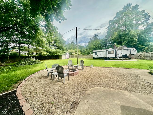 fenced backyard with a storage unit and an outdoor fire pit | Image 11