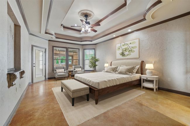 Bedroom featuring a tray ceiling, finished concrete flooring, ornamental molding, access to exterior, and recessed lighting | Image 15