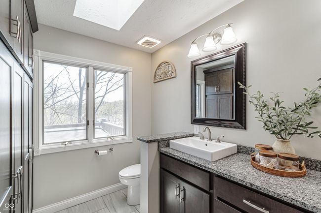 half bath featuring toilet, baseboards, visible vents, a skylight, and vanity | Image 26