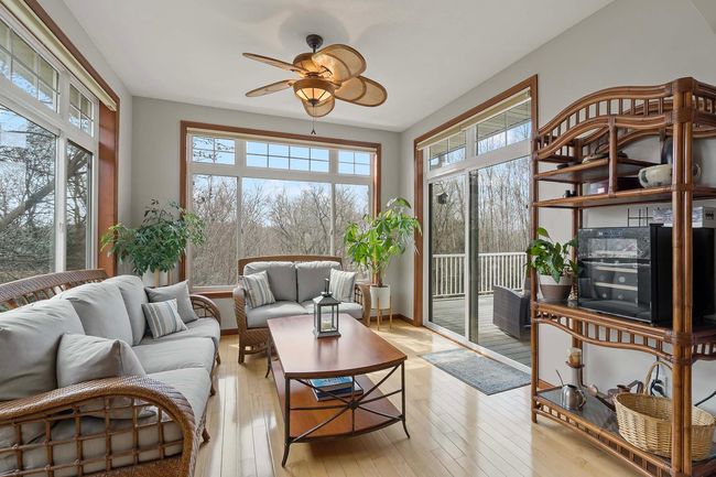 This bright sunroom is a highlight of the home. The sliding door opens to the maintenance-free deck that overlooks the wooded area behind the property. | Image 9