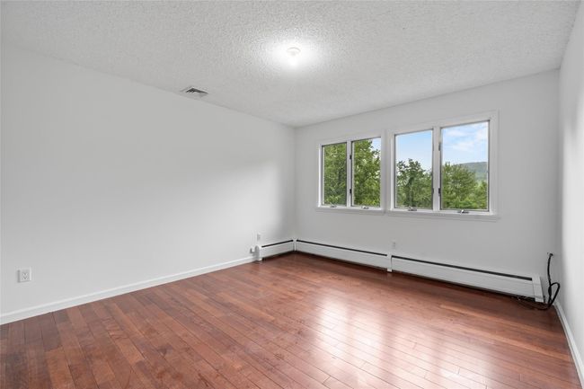 Spare room featuring a baseboard radiator, a textured ceiling, and dark wood finished floors | Image 23