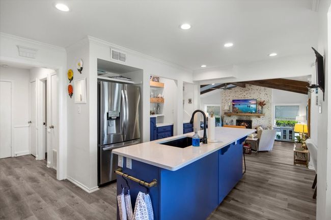 Kitchen featuring a sink, lofted ceiling with beams, blue cabinetry, visible vents, and stainless steel fridge with ice dispenser | Image 12