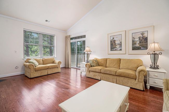 Living room with baseboards, dark wood-type flooring, crown molding, and high vaulted ceiling | Image 8