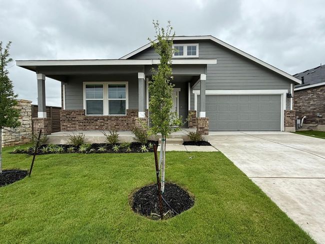 Craftsman house featuring covered porch, brick siding, driveway, an attached garage, and a front lawn | Image 4