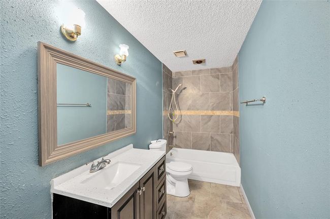 Modern guest bathroom featuring elegant tilework, a sleek vanity, and a cozy tub-shower combo. | Image 27