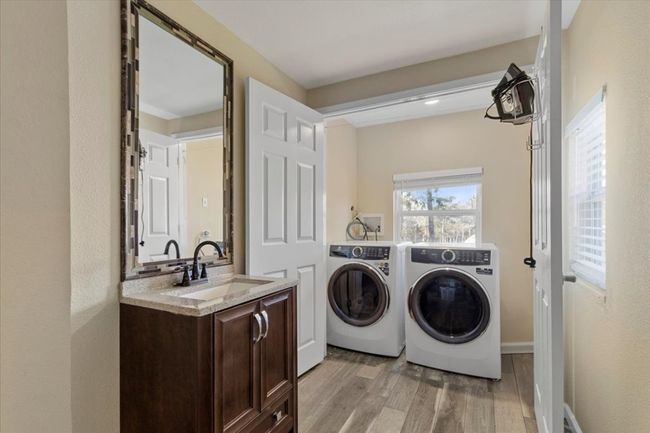 Clothes washing area with laundry area, a sink, light wood finished floors, and washing machine and clothes dryer | Image 21