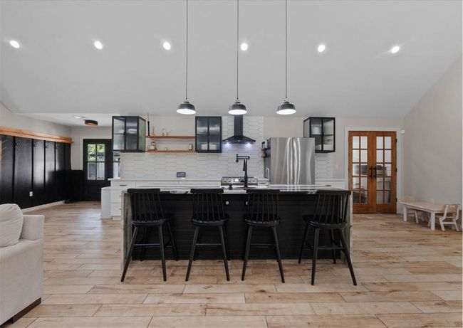 Gourmet kitchen with oversized island, custom backsplash, modern lighting, and stainless steel appliances | Image 19