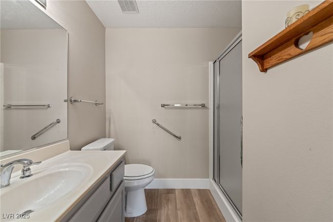 Bathroom featuring light wood-style flooring, a textured ceiling, a shower stall, and vanity | Image 23