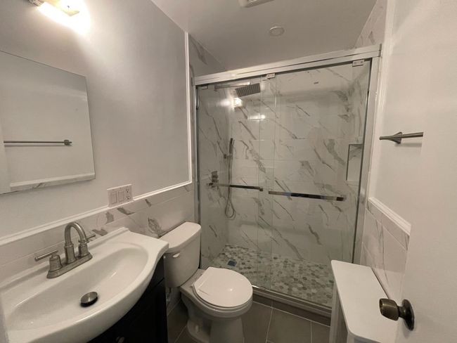 Full bath with tile walls, toilet, a marble finish shower, vanity, and wainscoting | Image 5