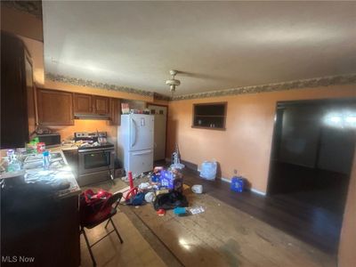 Kitchen featuring light wood-type flooring, stainless steel range with electric cooktop, and white refrigerator | Image 3