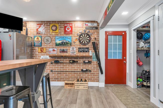 Bar featuring wood finished floors, brick wall, crown molding, and baseboards | Image 31