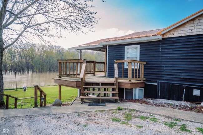 back of house with a deck with water view, metal roof, and a lawn | Image 8
