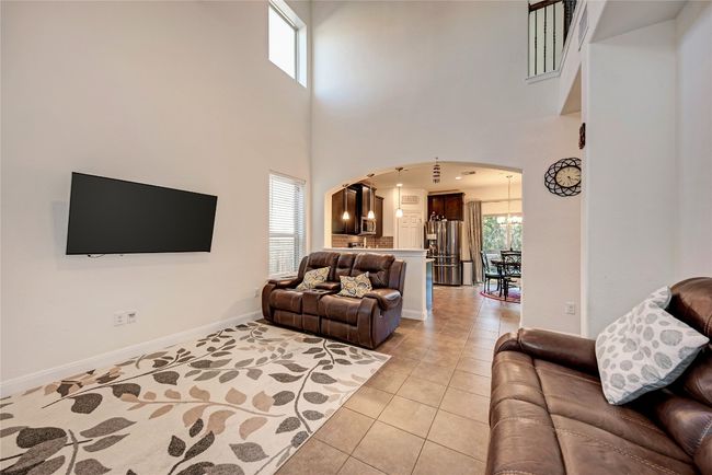 Living area with arched walkways, light tile patterned floors, a towering ceiling, and baseboards | Image 4