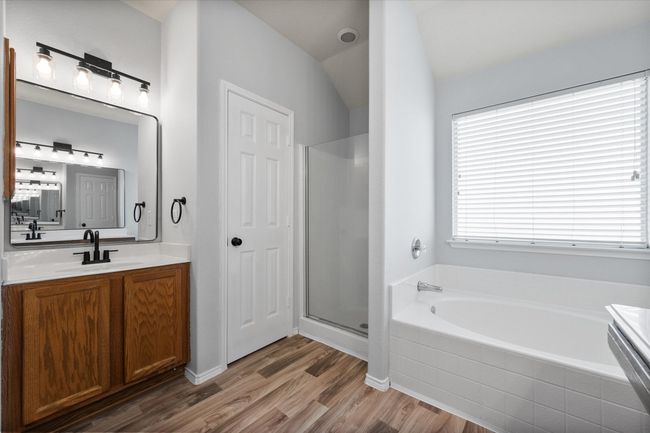 Bathroom featuring a bath, vanity, new laminate floors, and a stall shower | Image 26
