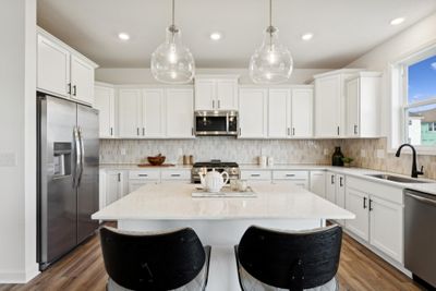 Photo is of the actual home. The stunning kitchen features a large center island, quartz countertops, LVP floors, stainless appliances and more. | Image 2